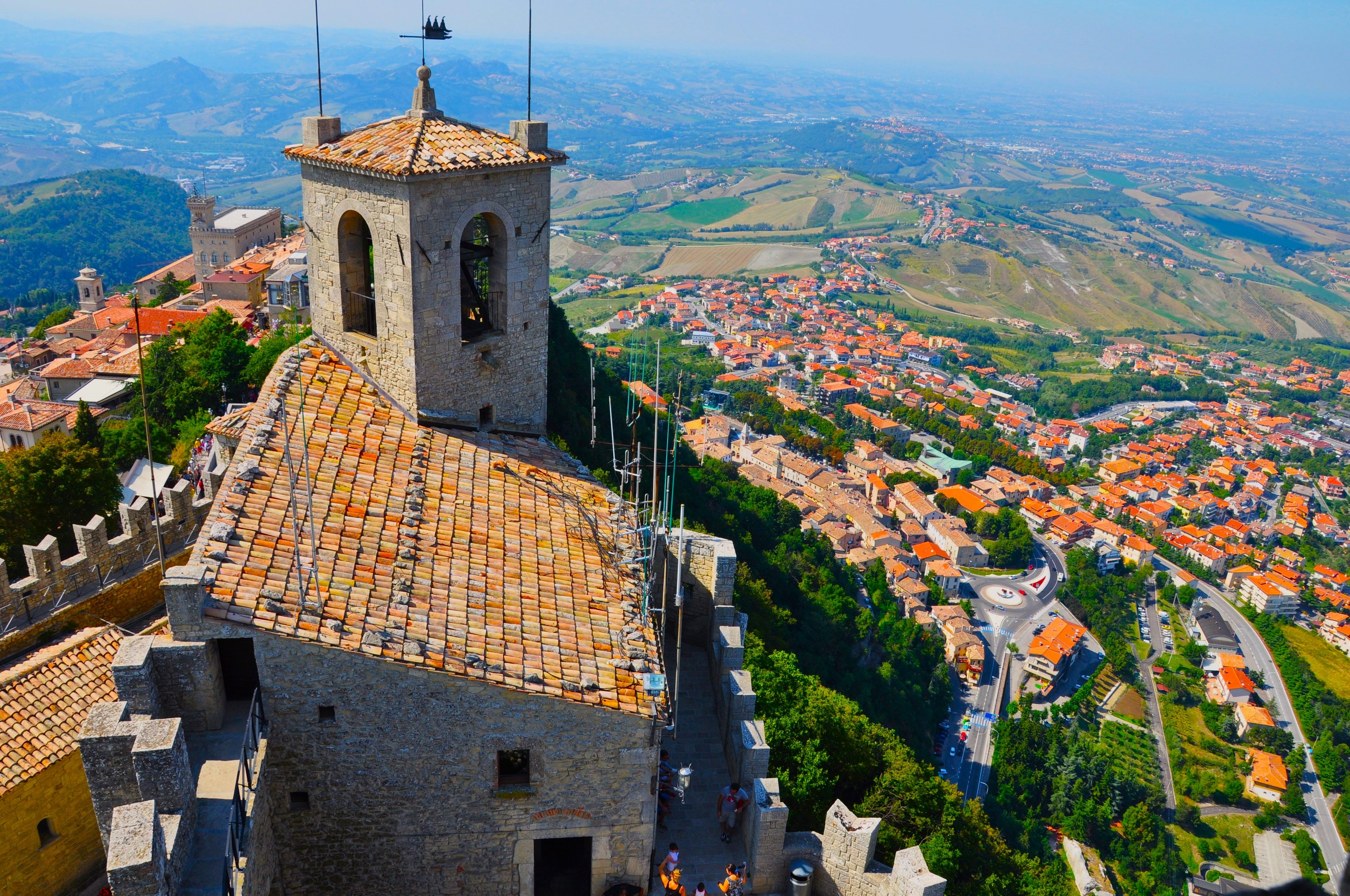 Breathtaking aerial photo of Guaita Tower and San Marino cityscape under clear skies.