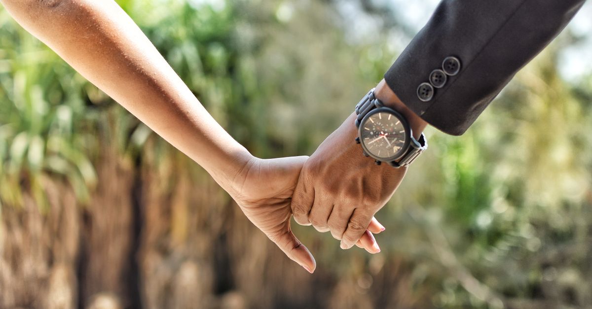 Romantic close-up of a couple holding hands in an outdoor setting, conveying love and connection.