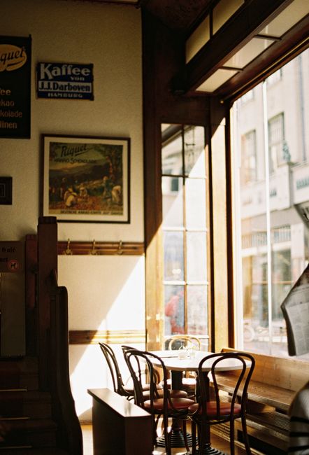 Warm sunlight illuminates a vintage café interior with classic decor and empty seating.