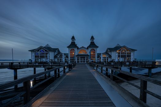 Beautiful evening view of the iconic Sellin Pier on Rügen Island, reflecting tranquil blues and warm lights.
