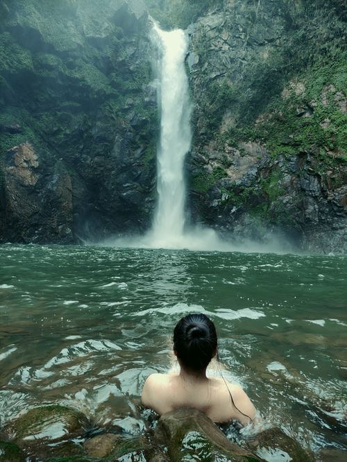 Free A peaceful scene of a person swimming near a stunning waterfall in Banaue, Philippines. Stock Photo