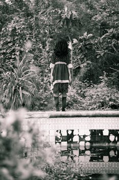 一张令人难以忘怀的黑白照片中，一个女孩独自站在废弃的游泳池里，四周环绕着茂密的树叶