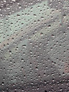 Close-up view of raindrops on a window forming an abstract texture, capturing nature's patterns.