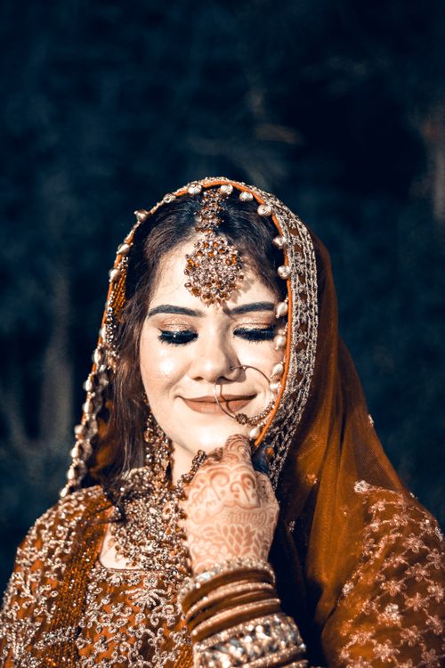 Free Stunning Indian bride with intricate jewelry and henna, captured in an outdoor setting. Stock Photo