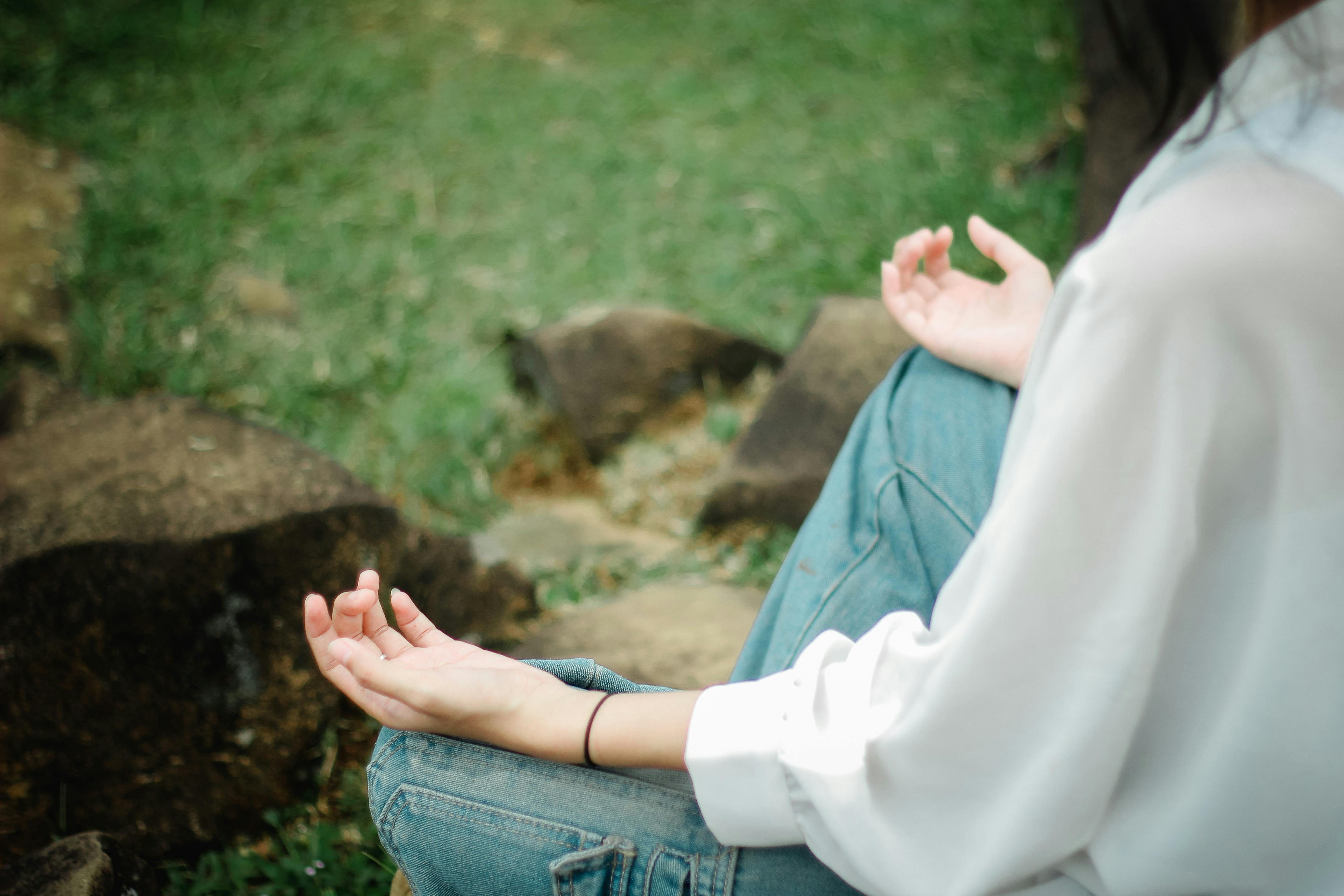 A person meditates outdoors, embracing tranquility and mindfulness.