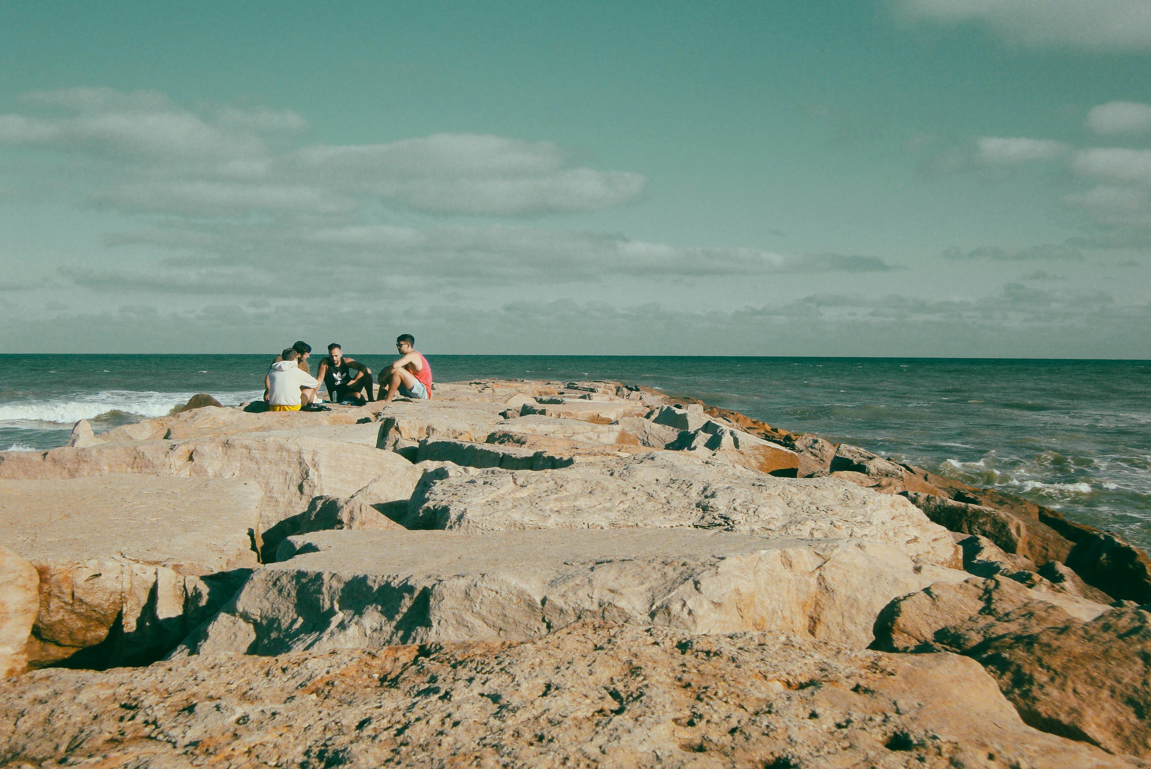 https://www.pexels.com/photo/friends-gather-on-rocky-pier-by-the-ocean-32097571/