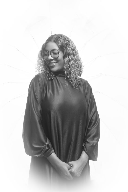 Free A smiling woman in a black dress with curly hair, captured in a black and white portrait. Stock Photo