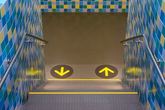 A vibrant indoor staircase with colorful tiles and direction arrows for guidance.