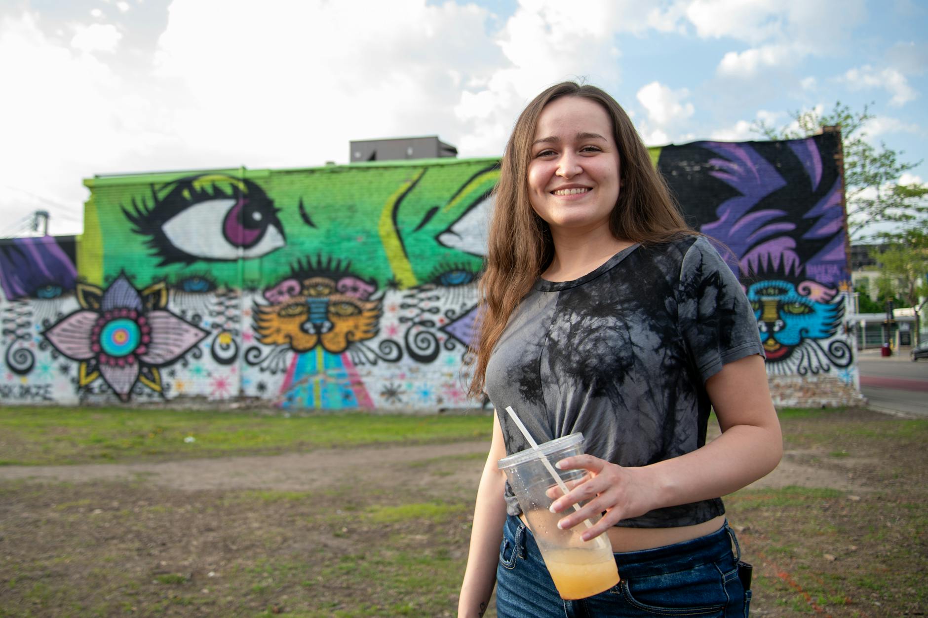 https://www.pexels.com/photo/smiling-woman-with-drink-in-urban-art-scene-32098069/