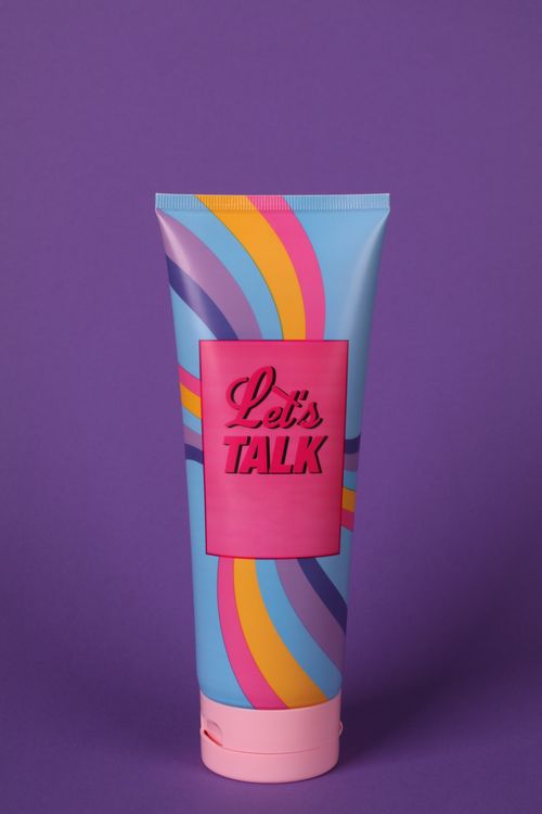 Free Vibrant cosmetic tube on purple background with 'Let's Talk' message. Stock Photo