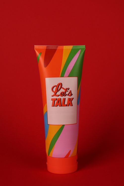 Free Brightly colored tube with 'Let's Talk' label against a red background, ideal for marketing. Stock Photo