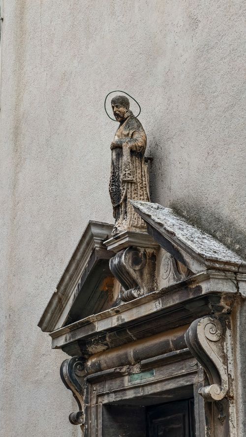 Free A weathered stone statue with a halo above an ornate doorway, showcasing historic architecture. Stock Photo