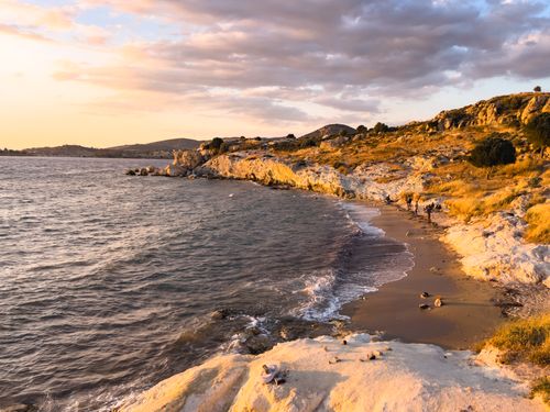 Free Scenic coastal view with rocky cliffs and sandy beach at sunset, capturing the serene beauty of nature. Stock Photo