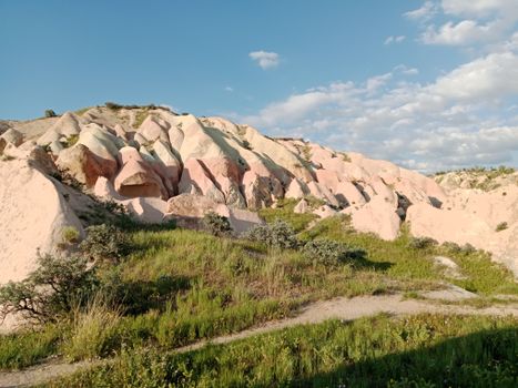 Stunning view of Cappadocia's unique rock formations and lush greenery under a bright blue sky.