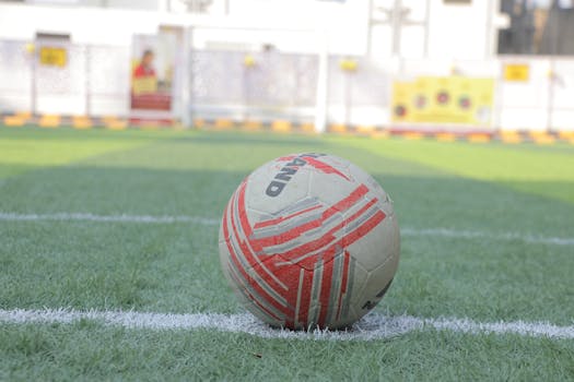 Close-up of a soccer ball on a green field with white lines, ready for play.