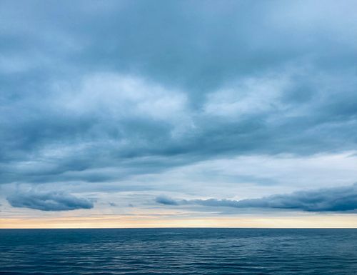 Free A tranquil seascape at twilight with dark clouds and calm ocean waves. Stock Photo