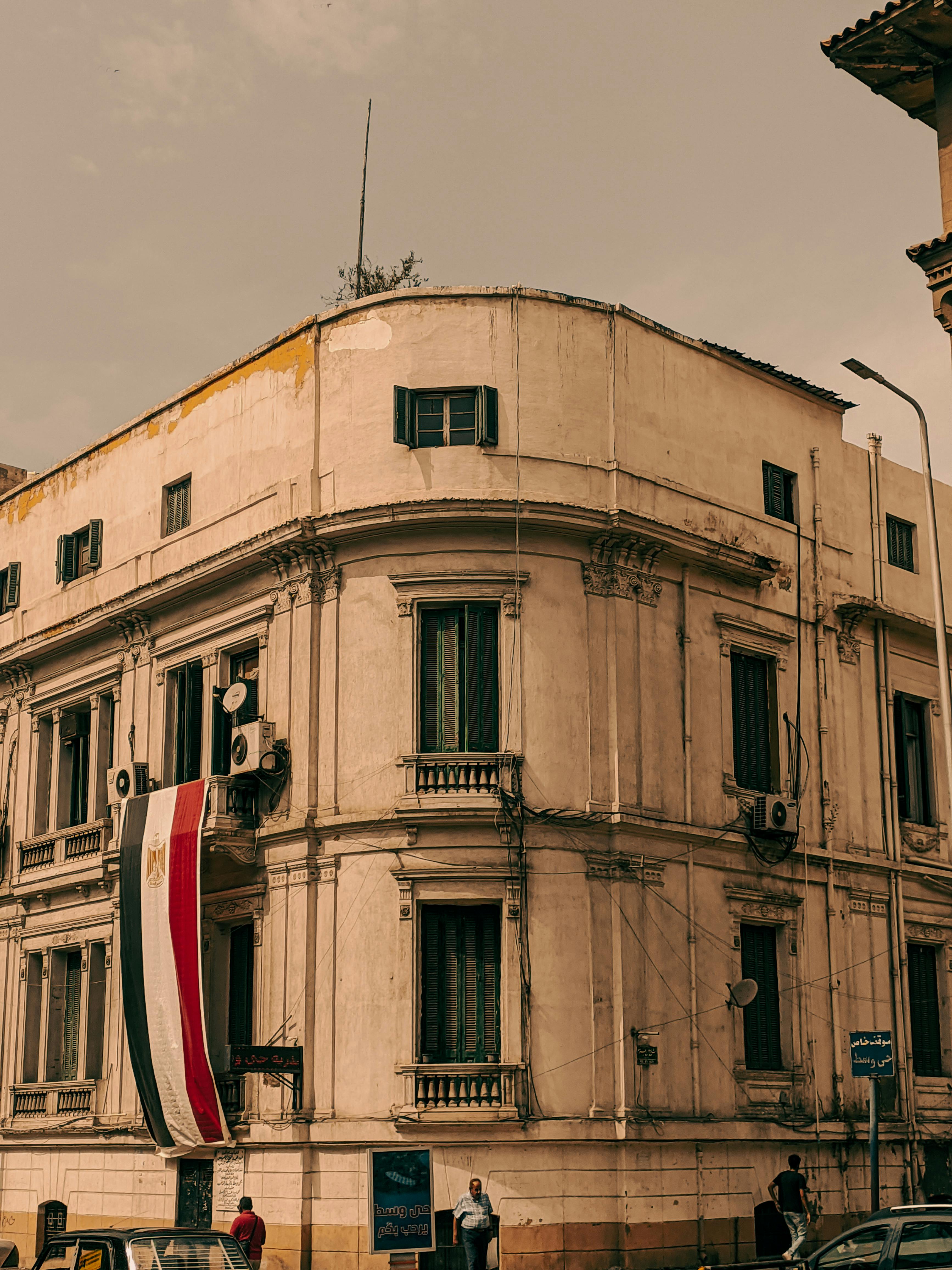 Free Vintage style building adorned with a flag on a corner street. Urban architectural beauty. Stock Photo