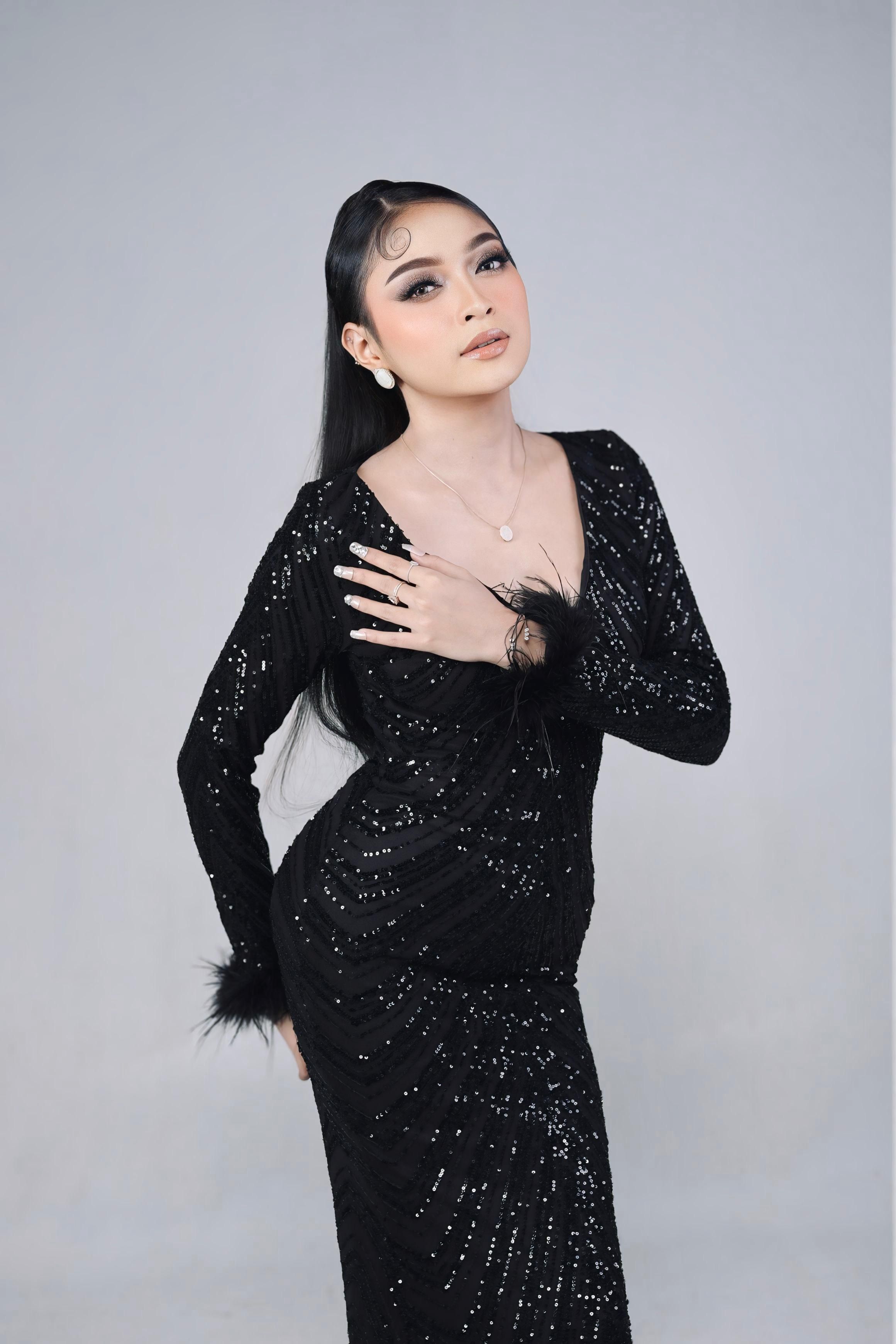 Elegant portrait of a woman in a glamorous black sequin dress, posing gracefully.