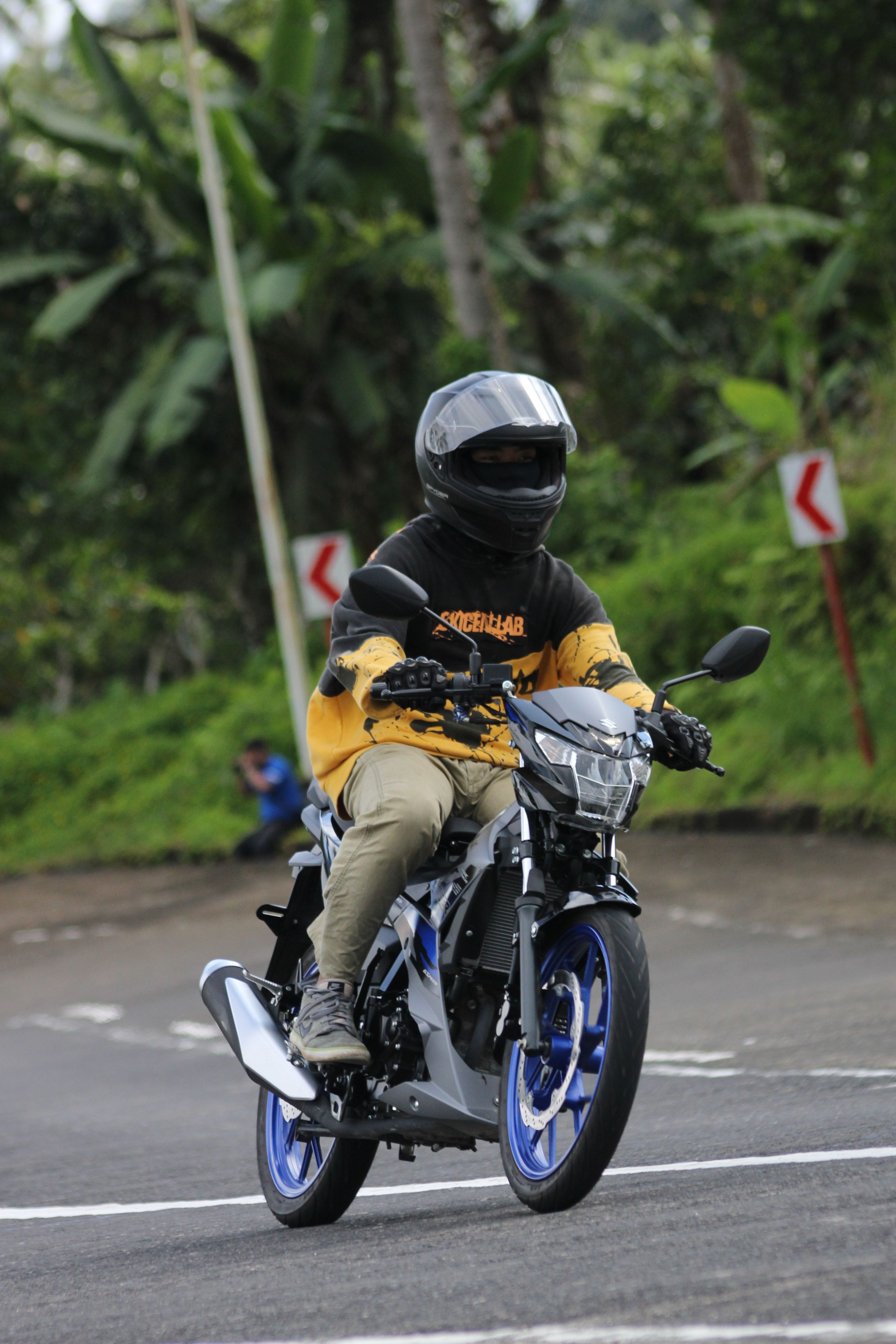 Motorcyclist on Curved Road in Lush Area