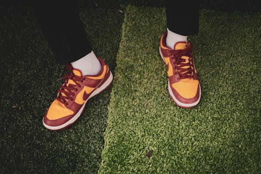 Stylish red and yellow sneakers on textured green grass in Baltimore.