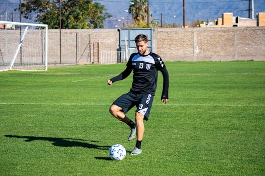A male footballer in action on a sunny day, showcasing soccer skills on a grassy field.