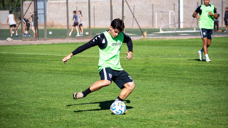 A young football player practicing with teammates on a sunny day outdoors.