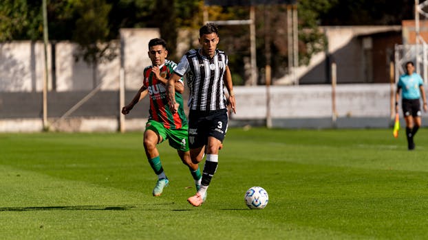 Two soccer players compete fiercely on an outdoor field during the day.