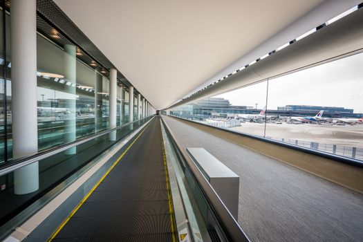 Sleek interior view of a Japanese airport terminal with a moving walkway and airplanes visible outside.
