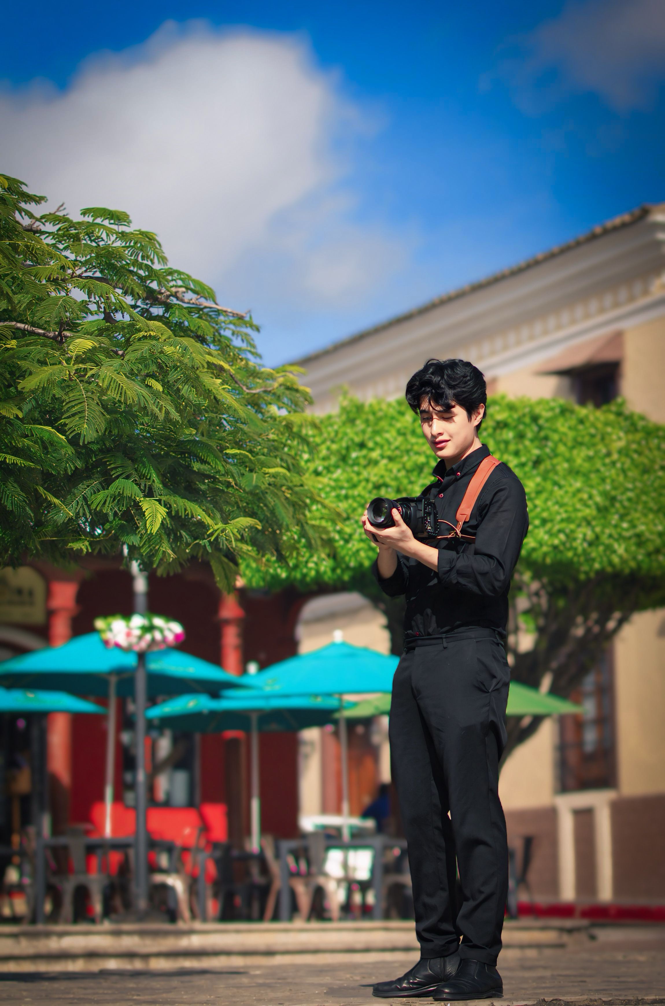 Young photographer capturing moments outdoors with colorful urban backdrop.