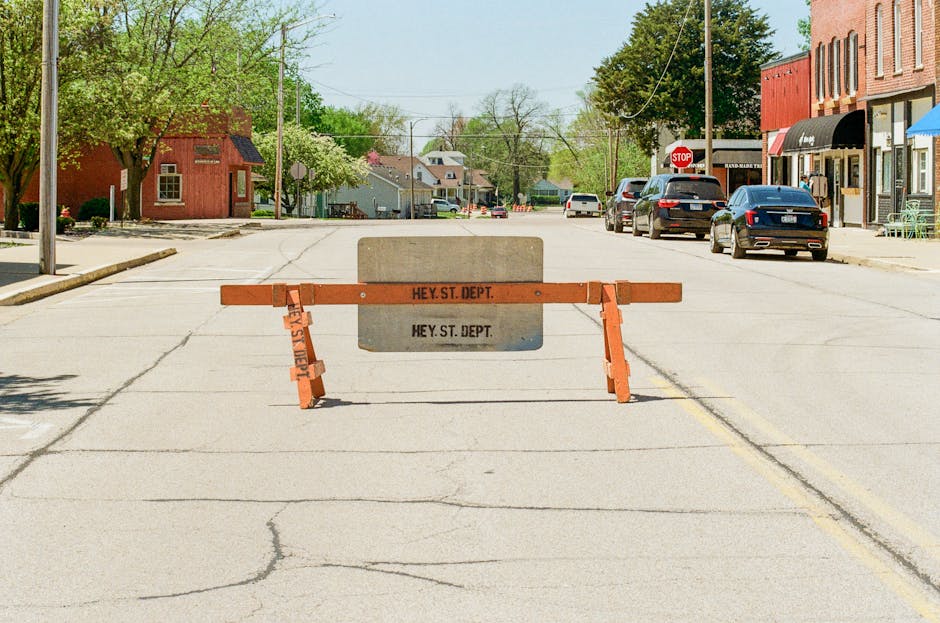 Photo by J.S. McDuff Empty city street with a barrier indicating closed road in a sunny neighborhood.