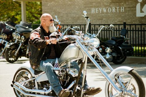 Free A man rides a custom chopper motorcycle on a sunny day outside a cafe. Stock Photo