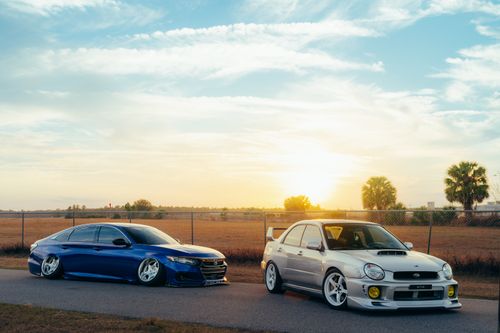 Free Two modified sedans parked with a stunning sunset backdrop, showcasing sleek designs. Stock Photo