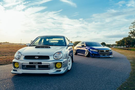 Stylish modified cars parked on a scenic road during sunset, showcasing sleek design and vibrant colors.