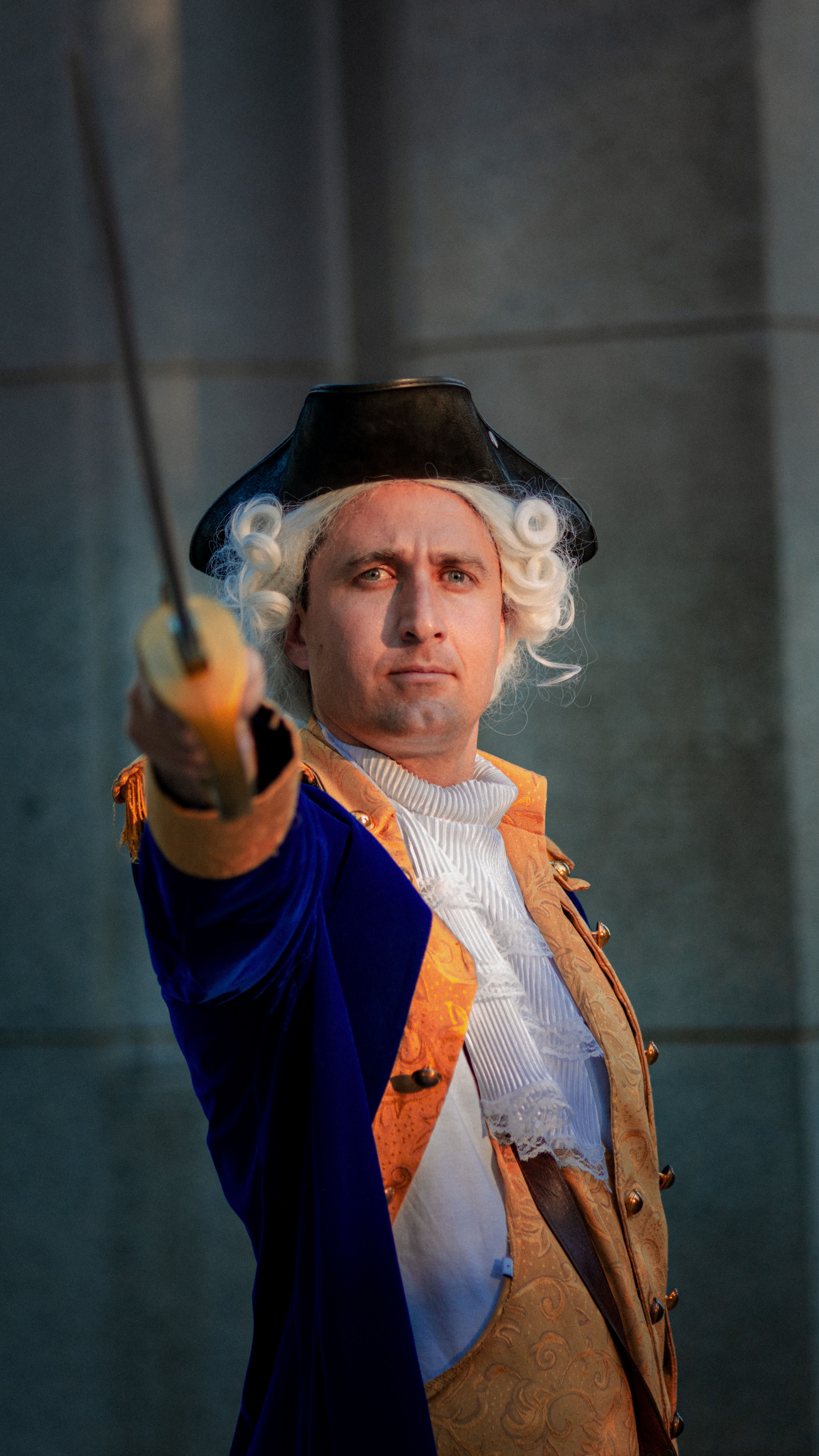 A historical reenactor in 18th-century clothing holds a sword in Washington, DC.