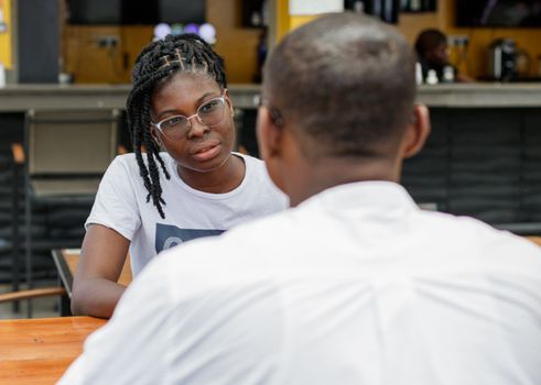 A casual interaction between two adults at a lively cafe in Accra, Ghana.