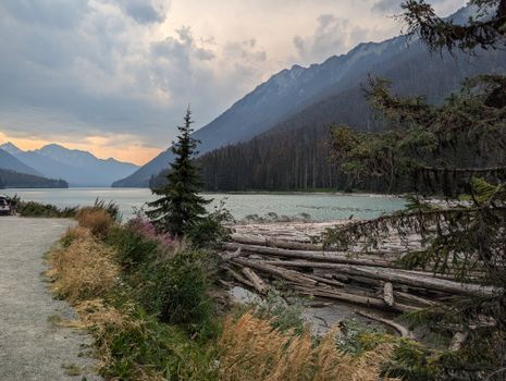 Serene landscape of a lake surrounded by mountains and forests in British Columbia at sunset.