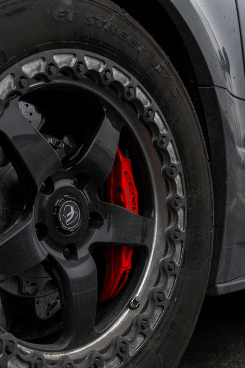 Free Detailed view of a car wheel with striking red brake caliper, showcasing automotive design. Stock Photo