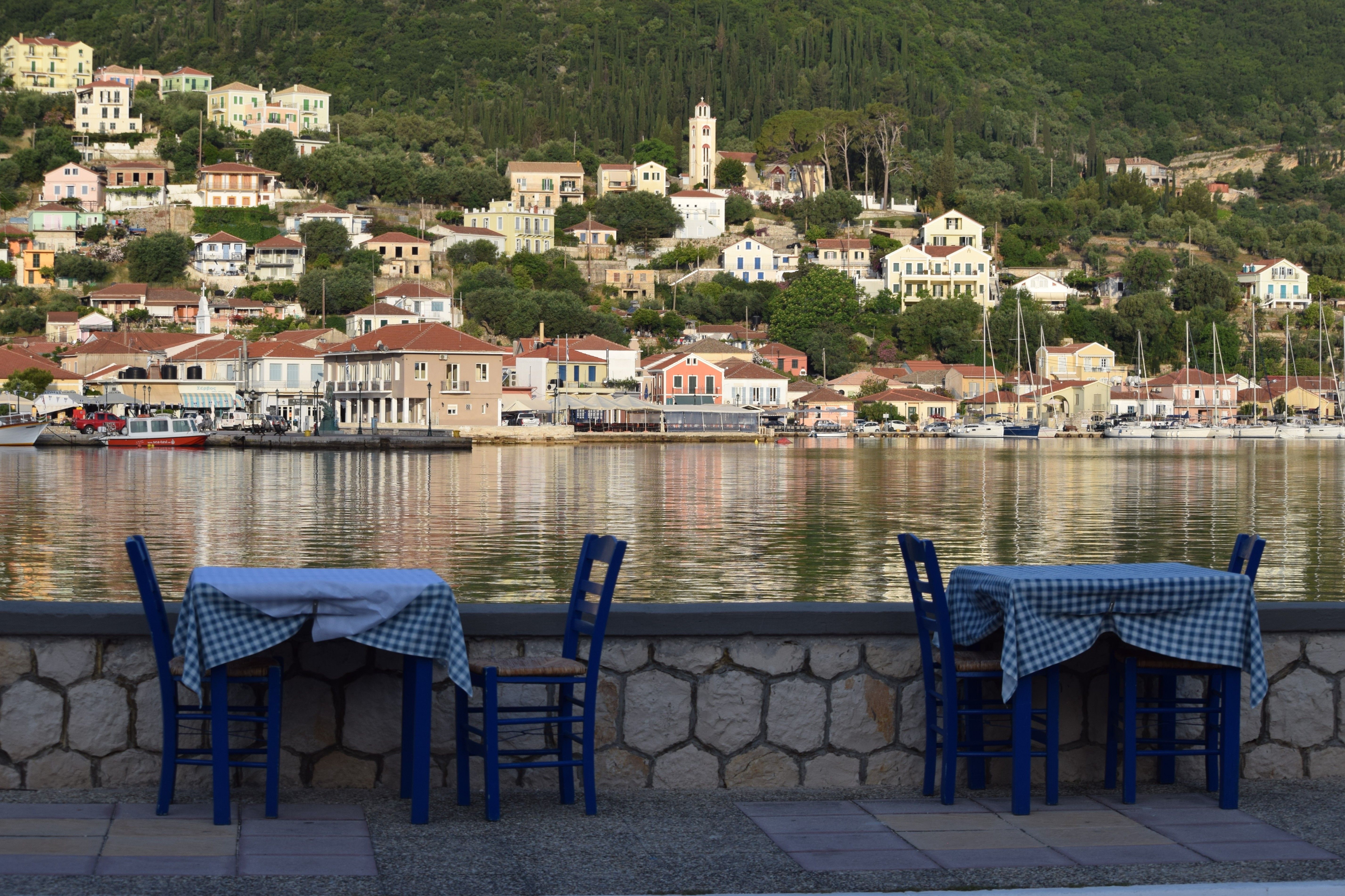 Picturesque dining setup by the sea on a Greek island with beautiful hillside view.