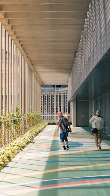 Two adults walking along a modern architectural corridor in daylight.
