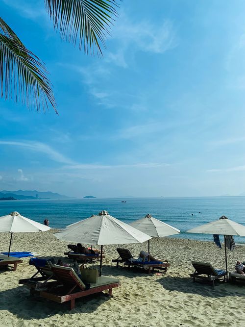 Free A serene beach day with sun umbrellas and lounge chairs by the sea under a clear blue sky. Stock Photo