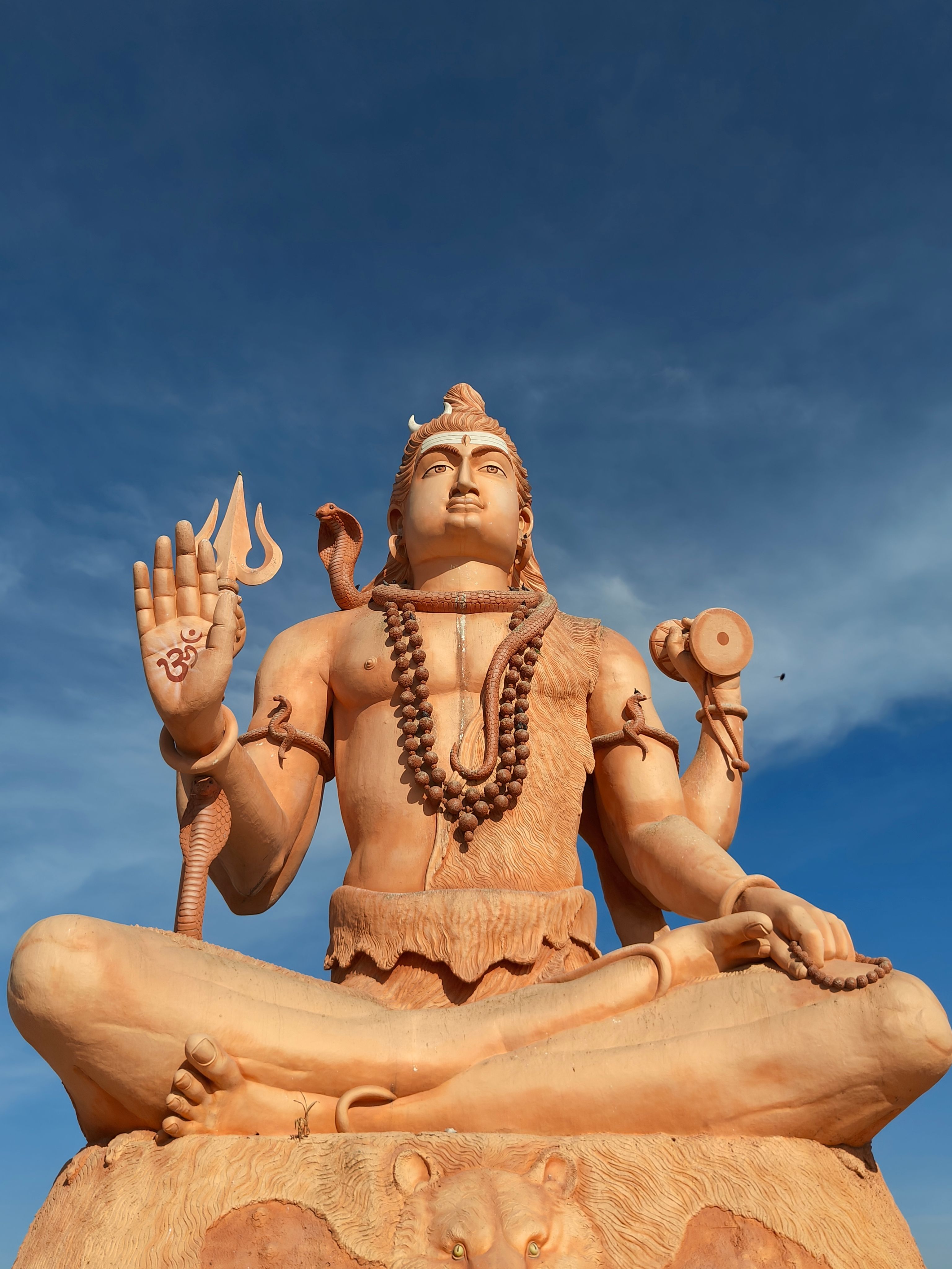 A captivating statue of Lord Shiva, depicted in a meditative pose against a clear blue sky.