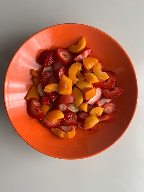 Free Bright orange bowl filled with fresh strawberry and apricot slices, showcasing vibrant and healthy fruit snack. Stock Photo