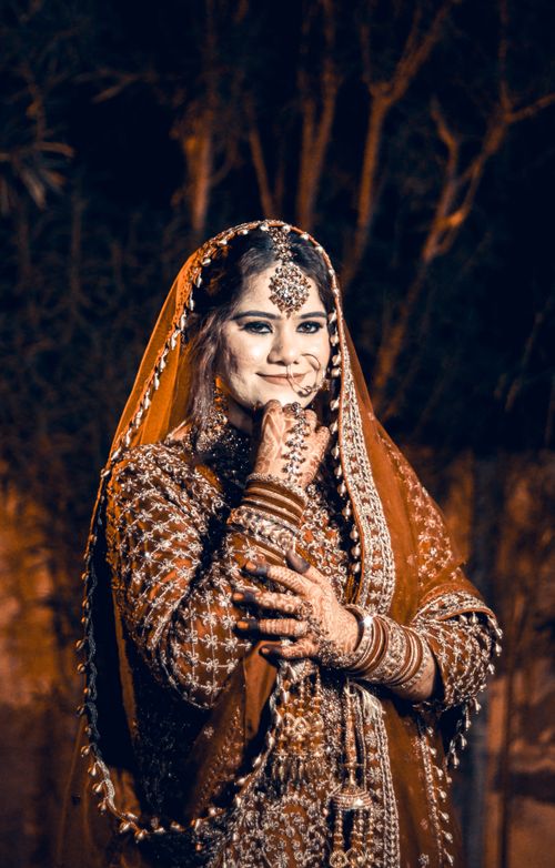Free Graceful Indian bride in traditional attire with intricate henna design, elegantly posing at a night wedding ceremony. Stock Photo