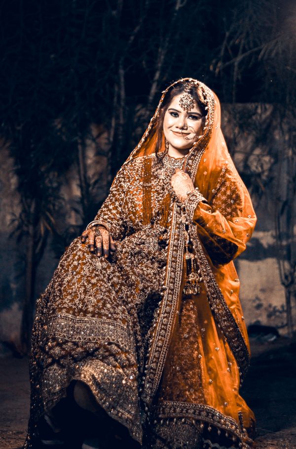 Indian bride in ornate traditional attire at an outdoor wedding