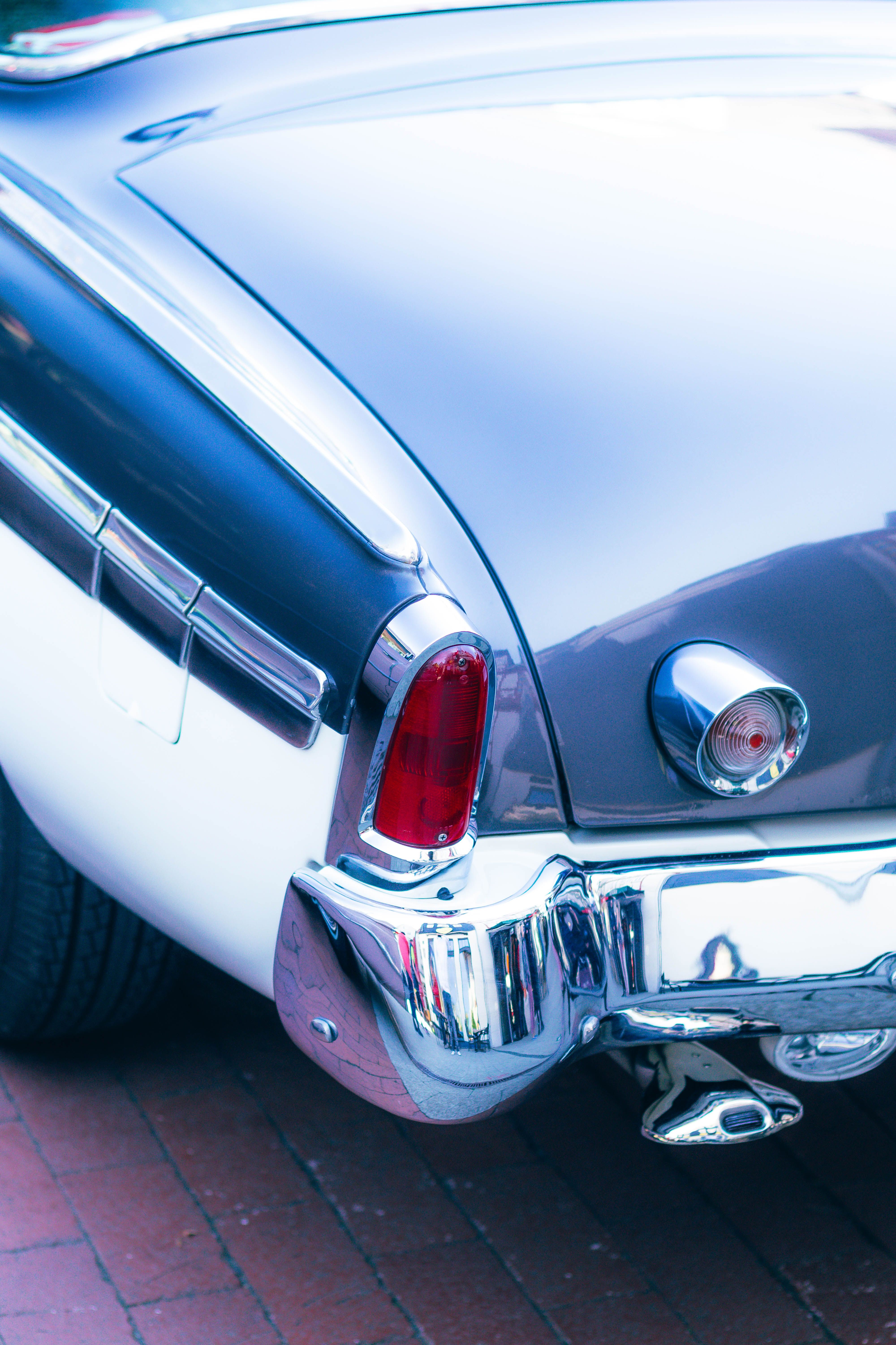 A close-up view of a sleek, vintage car's rear with chrome details, captured in bright summer light.