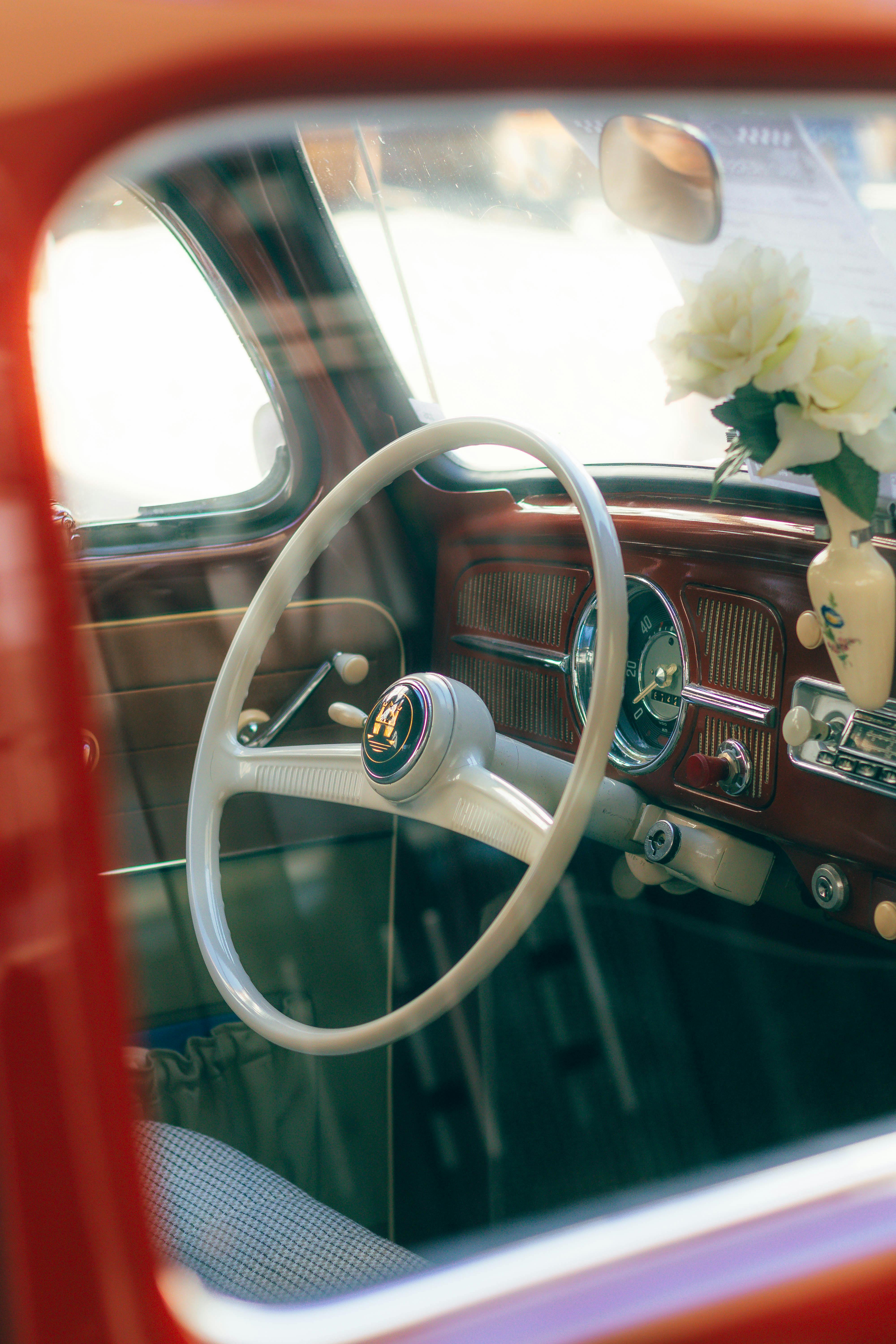 Close-up of a vintage car interior featuring a classic steering wheel and floral decoration.
