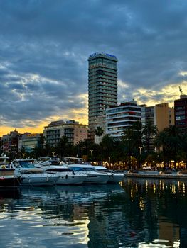 Twilight view of Alicante harbor with yachts and city skyline, capturing the evening ambiance.