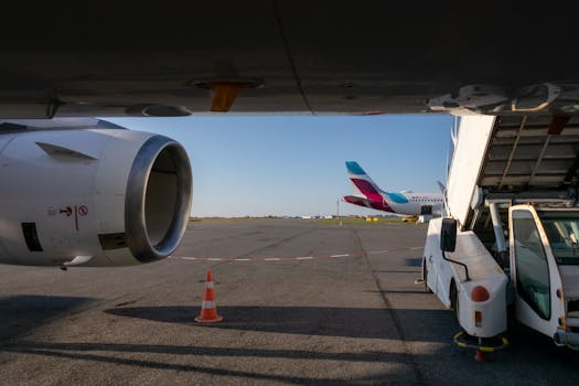 View of airplane turbine and jet bridge at airport with clear skies.