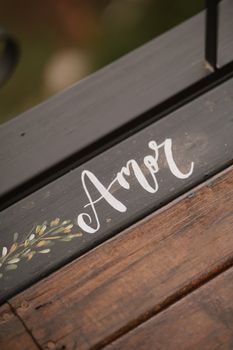 Close-up of 'Amor' artfully painted on rustic wood, capturing elegance and romance.