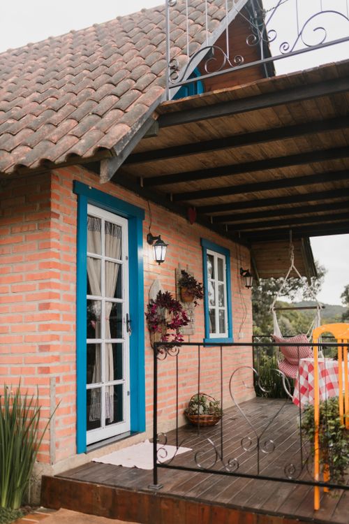 Free Inviting rustic porch with brick walls, blue accents, and cozy decor in a tranquil setting. Stock Photo